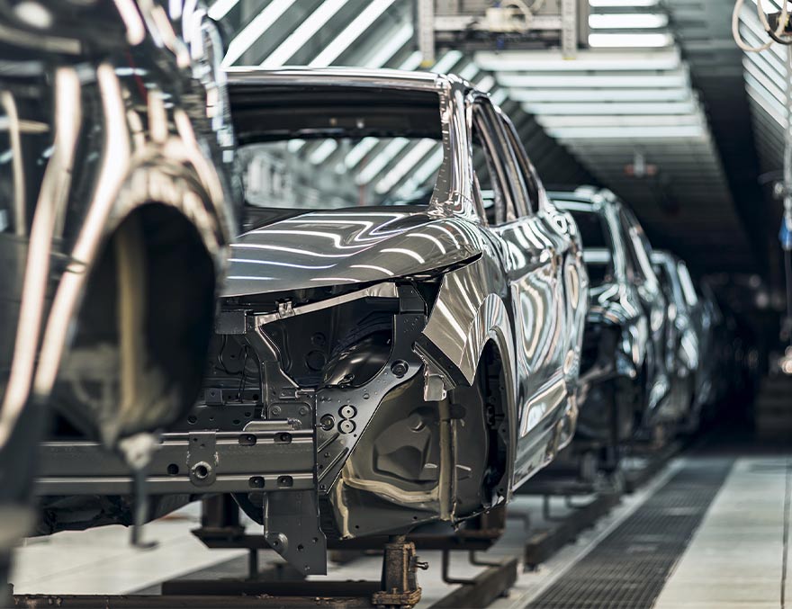 Looking down a row of autos being manufactured in a factory.