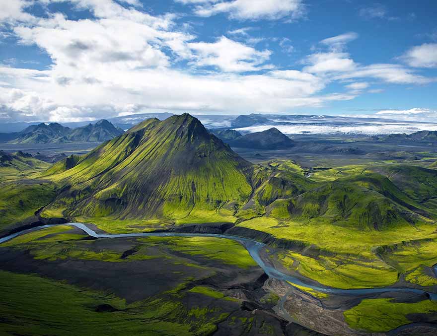 Aerial view of a mountainous landscape with green forests and a river.