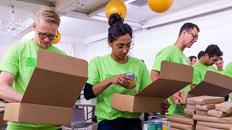 People packing items into a cardboard box. 